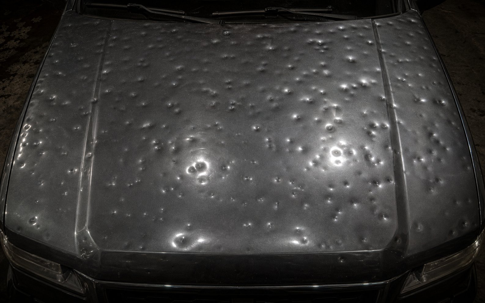 Truck hood covered in hail dents — before