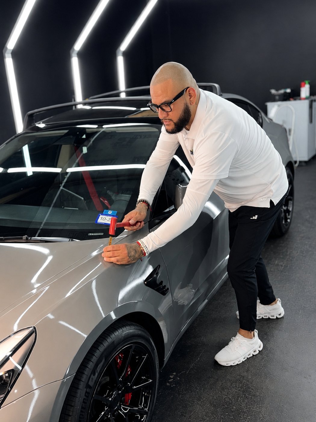 Lone Star PDR master technician performing paintless dent repair on a Tesla under calibrated light lines